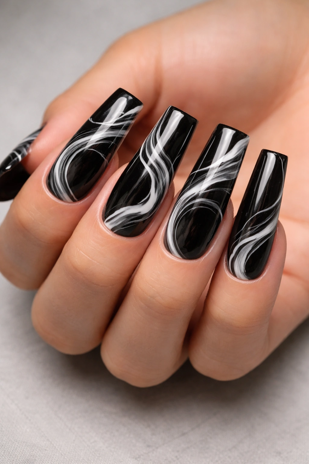 Close-up of long duck nails with a glossy black base and white marble swirls