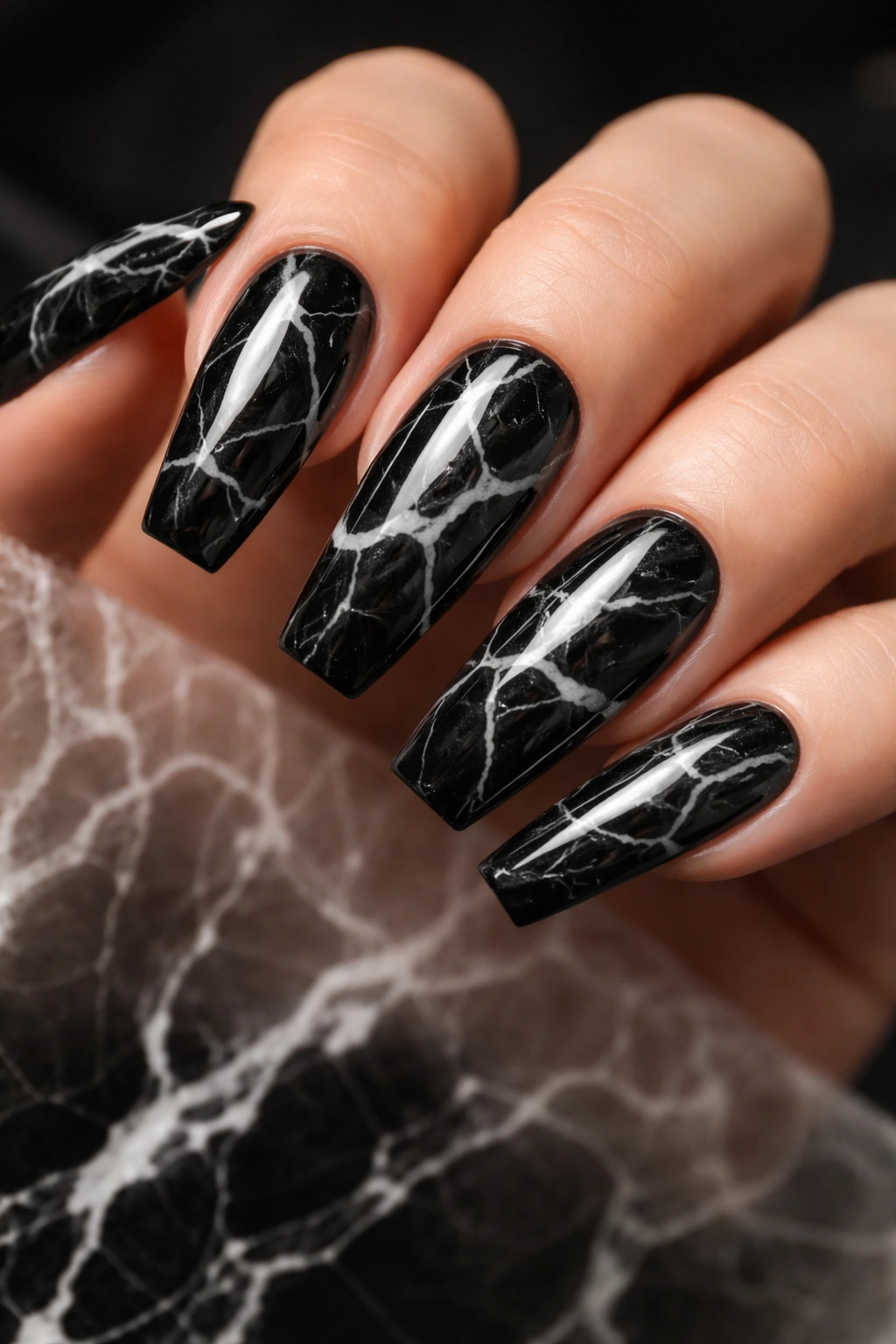 Black marble nails with white veining on a hand