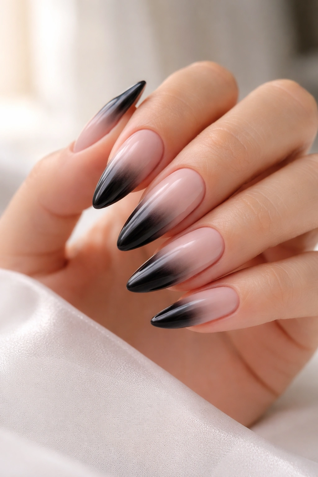 Almond nails with milky pink base and black gradient at tips