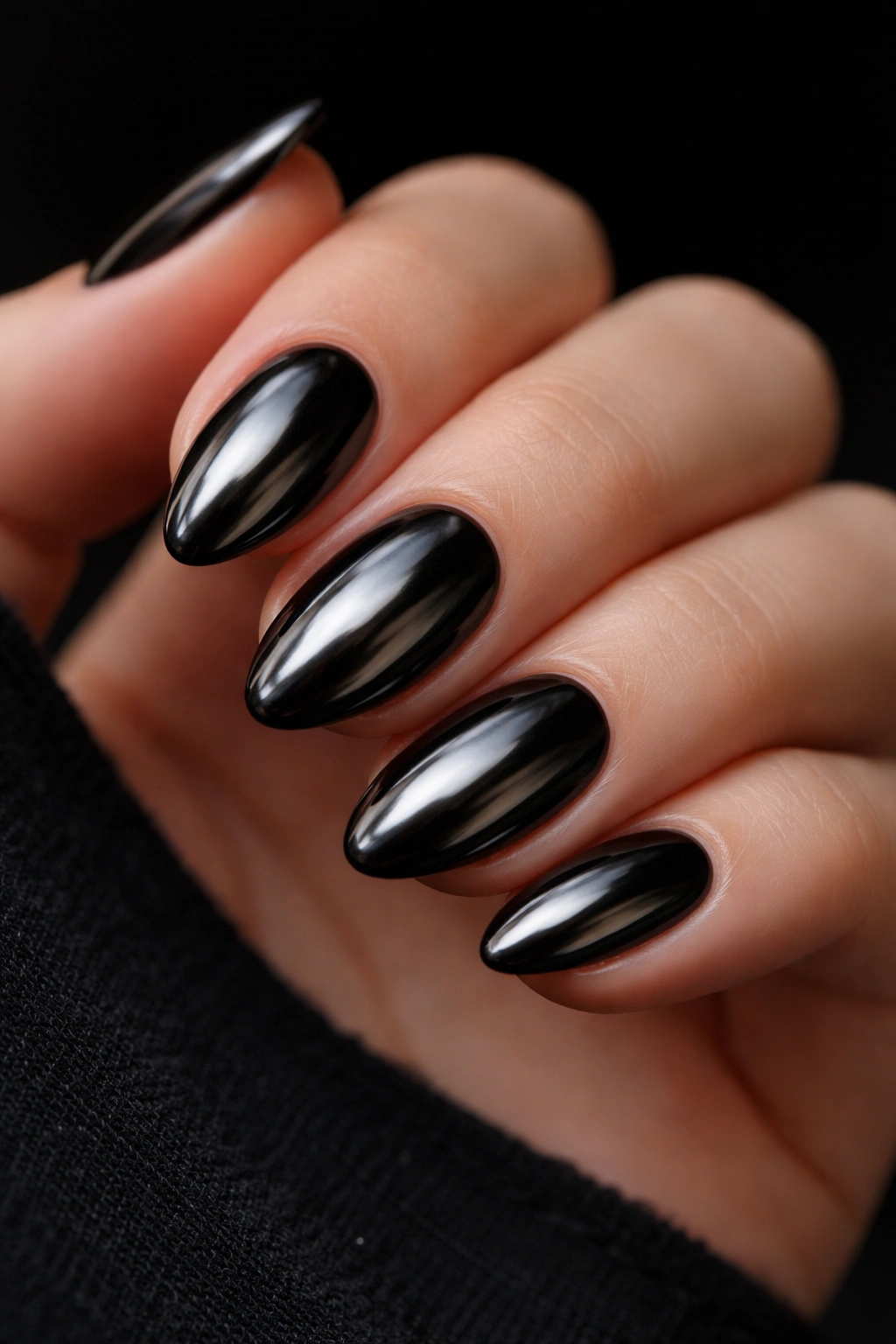 Short almond nails with black chrome finish reflecting light