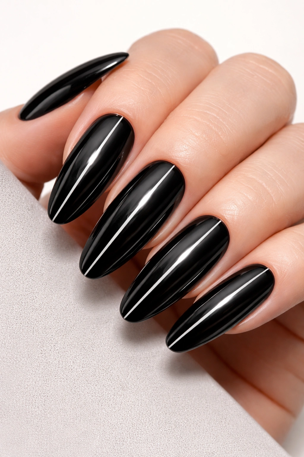 Close-up of glossy black oval nails with a chrome center line