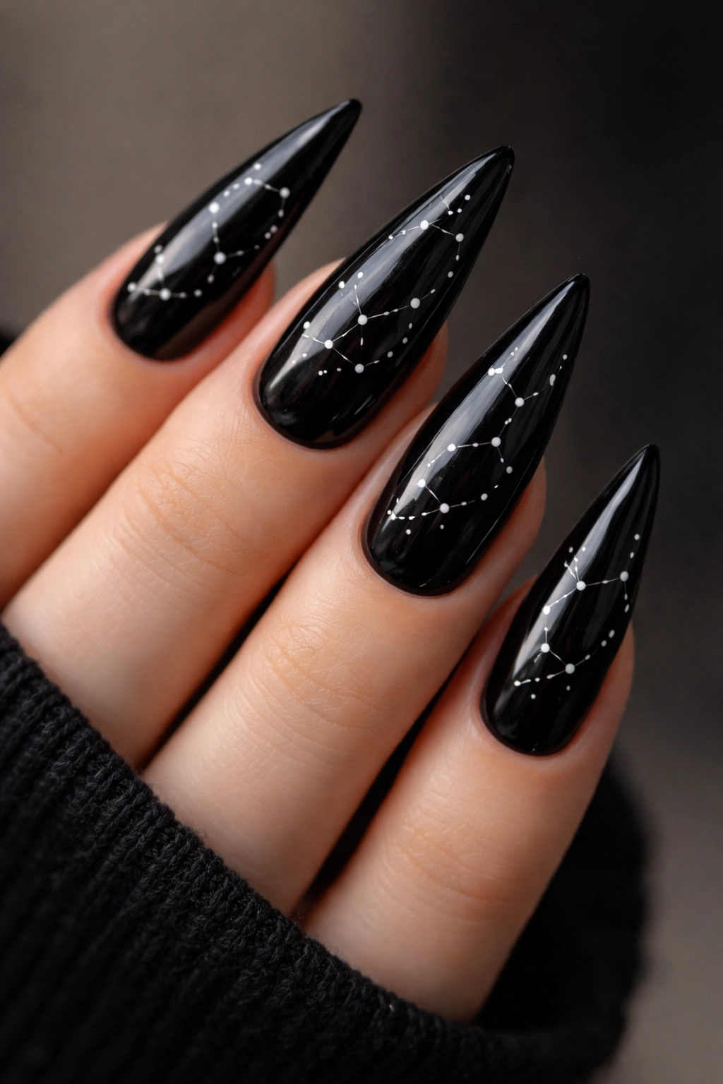 Close-up of glossy black stiletto nails with constellation dot patterns