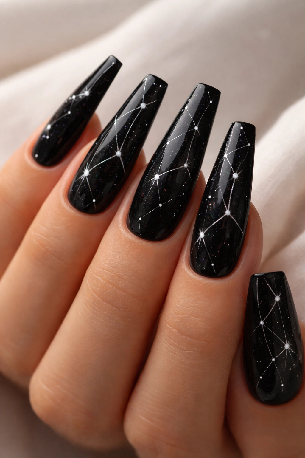 Close-up of black coffin nails with delicate white constellation patterns.