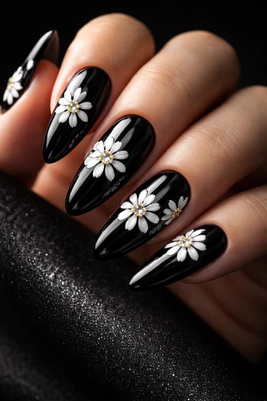 Close-up of black nails with white daisies and rhinestone centers