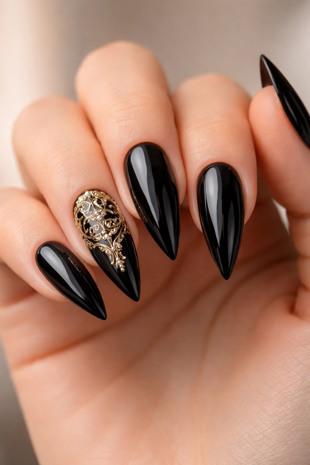 Close-up of glossy black stiletto nails with intricate gold filigree detailing.
