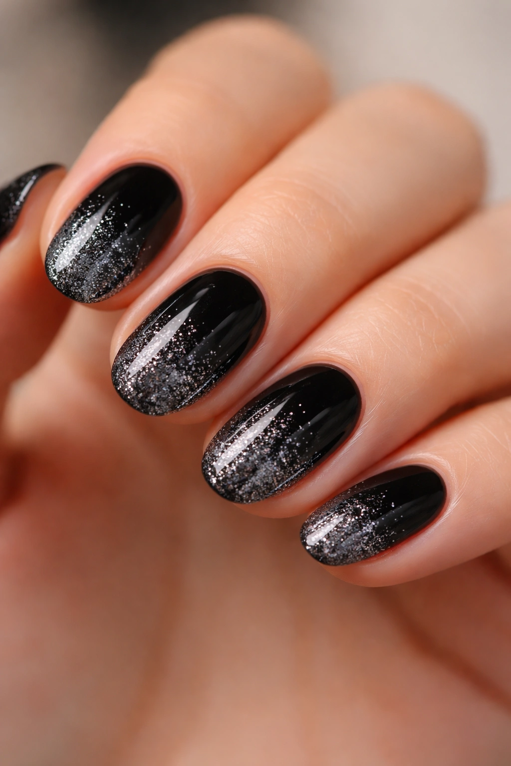 Close-up of black nails with glitter fade at the tips