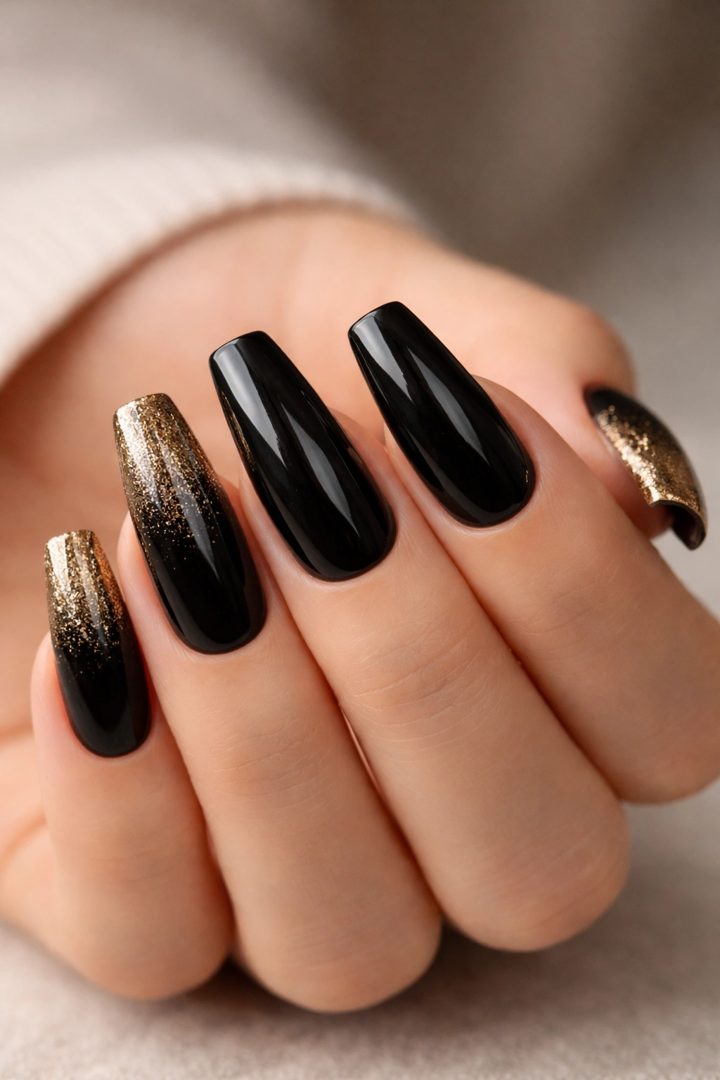 Close-up of medium coffin nails with black polish and gold glitter gradient at tips