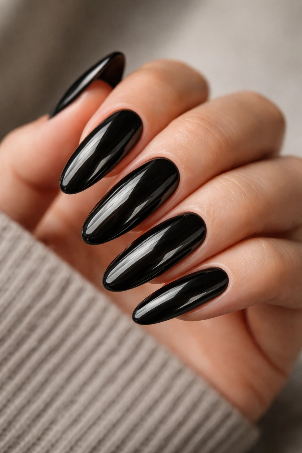 Close-up of long oval black glossy acrylic nails on a hand with high shine
