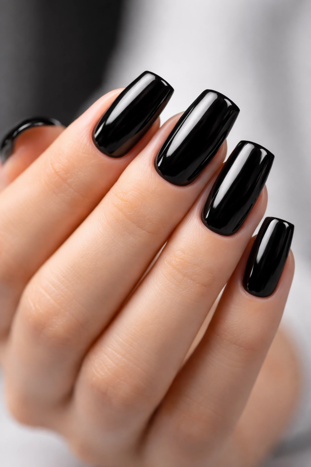Close-up of glossy black nails on a clean neutral background