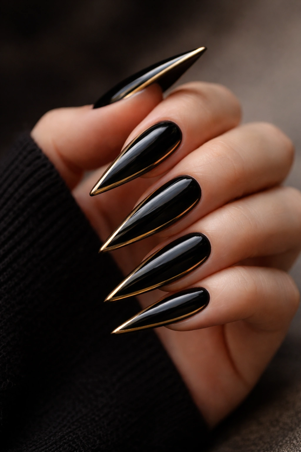 Close-up of black stiletto nails with gold accents