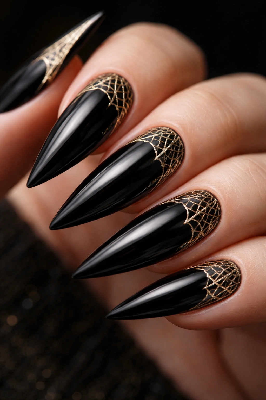 Close-up of black stiletto nails with gold cobweb corner details