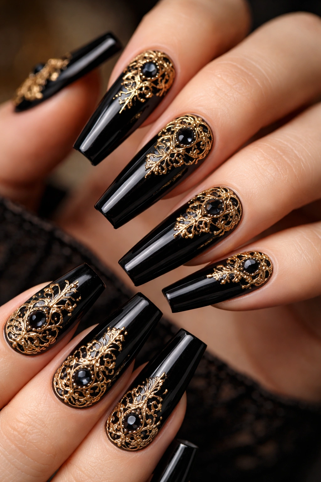 Glossy black coffin nails with delicate gold filigree and dark gemstones