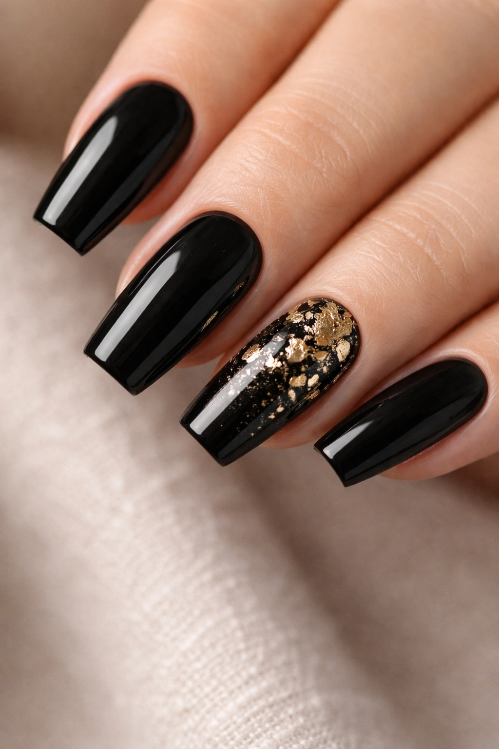 Nails with black base and gold foil accent on one nail