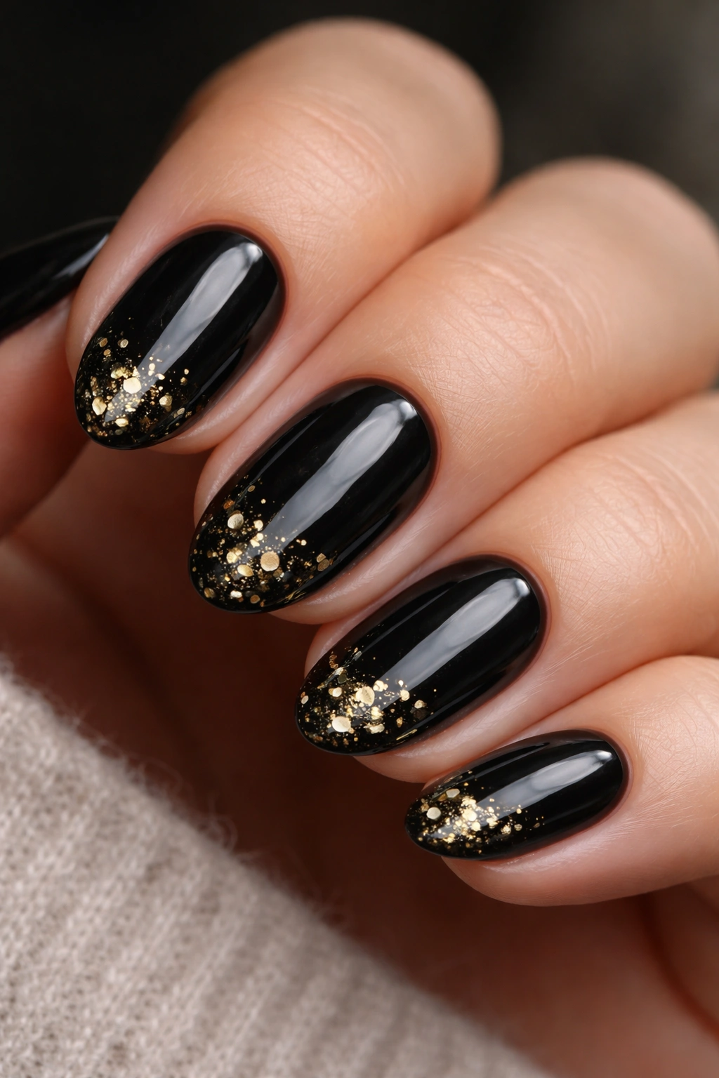 Short almond nails in glossy black with tiny gold foil accents