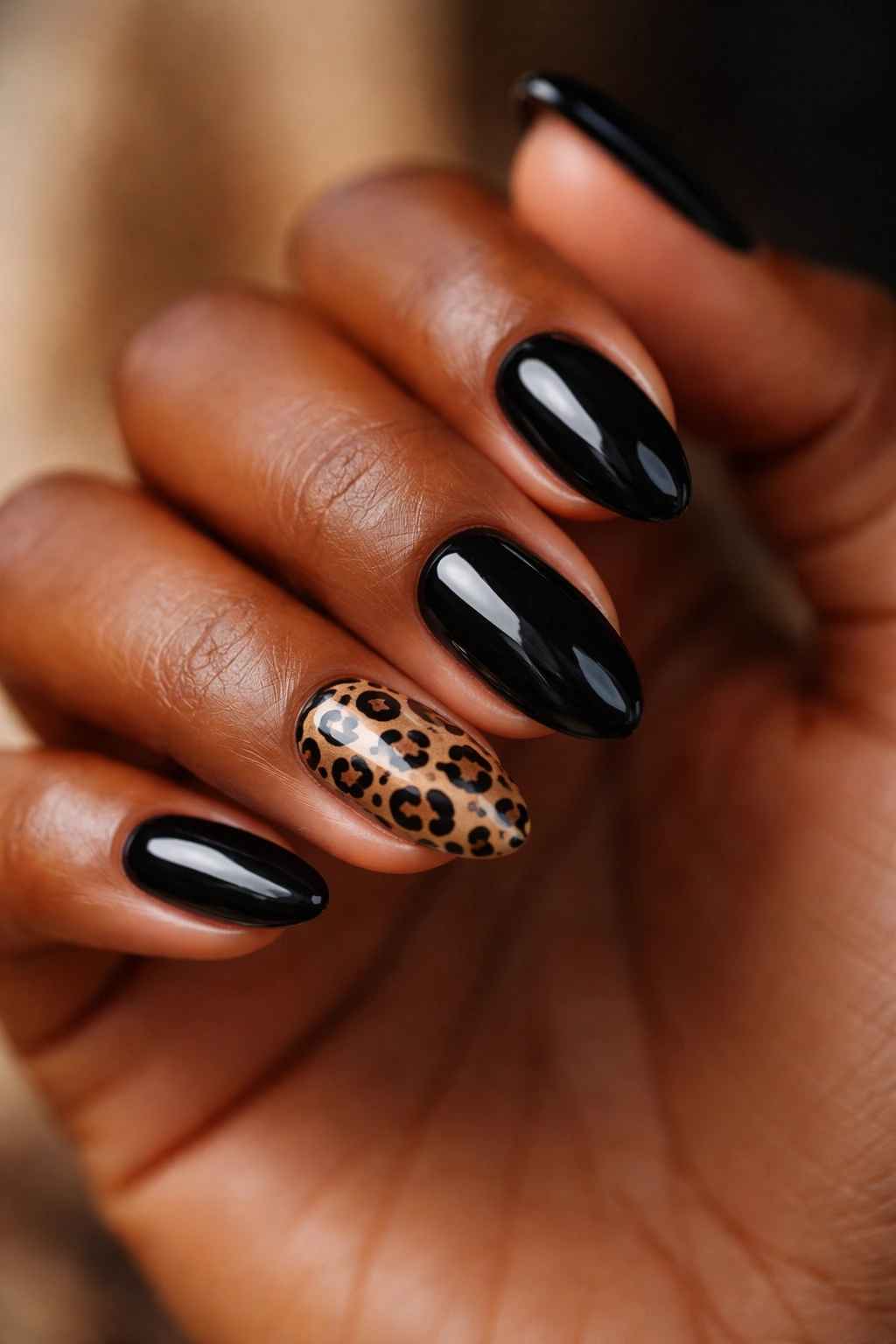 Close-up of black almond nails with a small leopard accent nail on dark skin