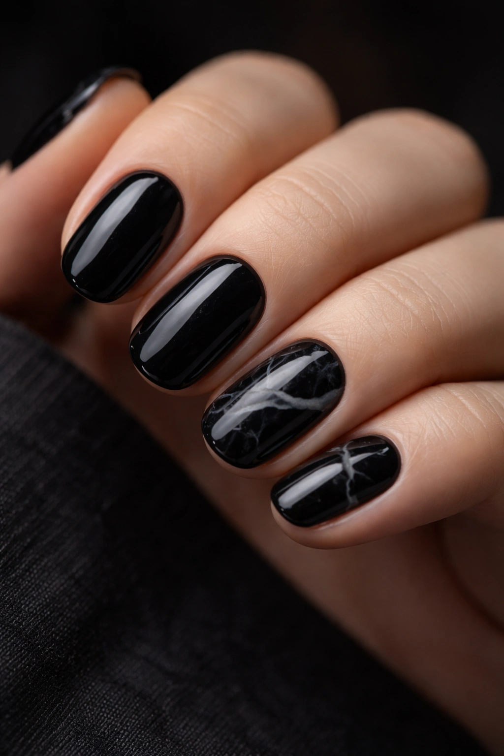 Close-up of short black nails with marble pattern and gray veins