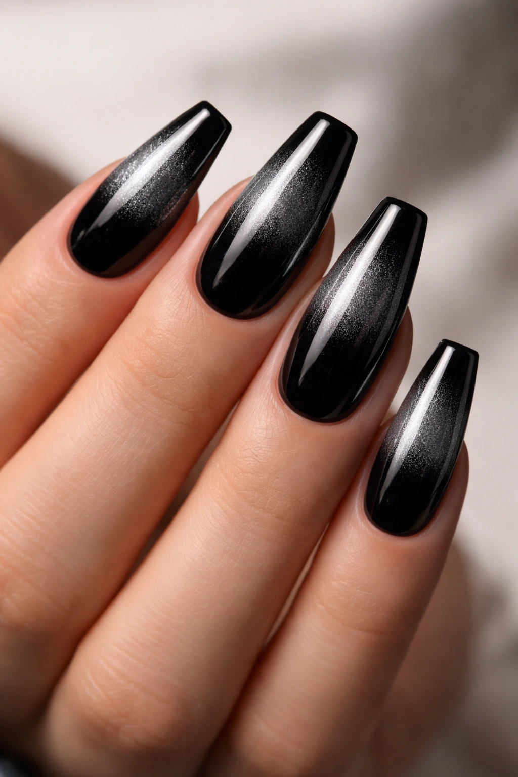 Coffin nails with black base fading into chrome tips under studio lighting