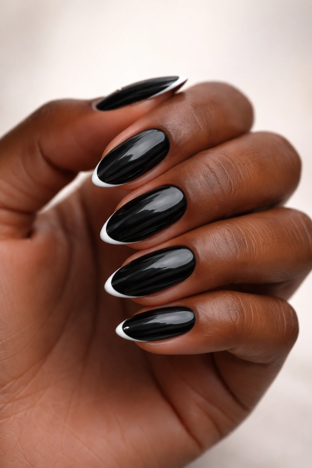 Close-up of black almond nails with a thin white micro French tip