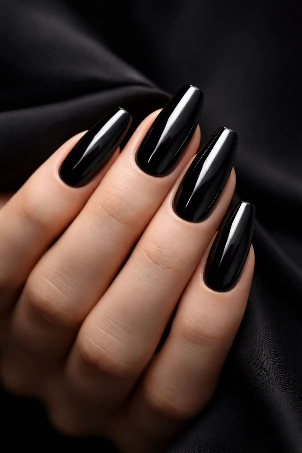 Close-up of sleek black nails on a hand with a dark background.