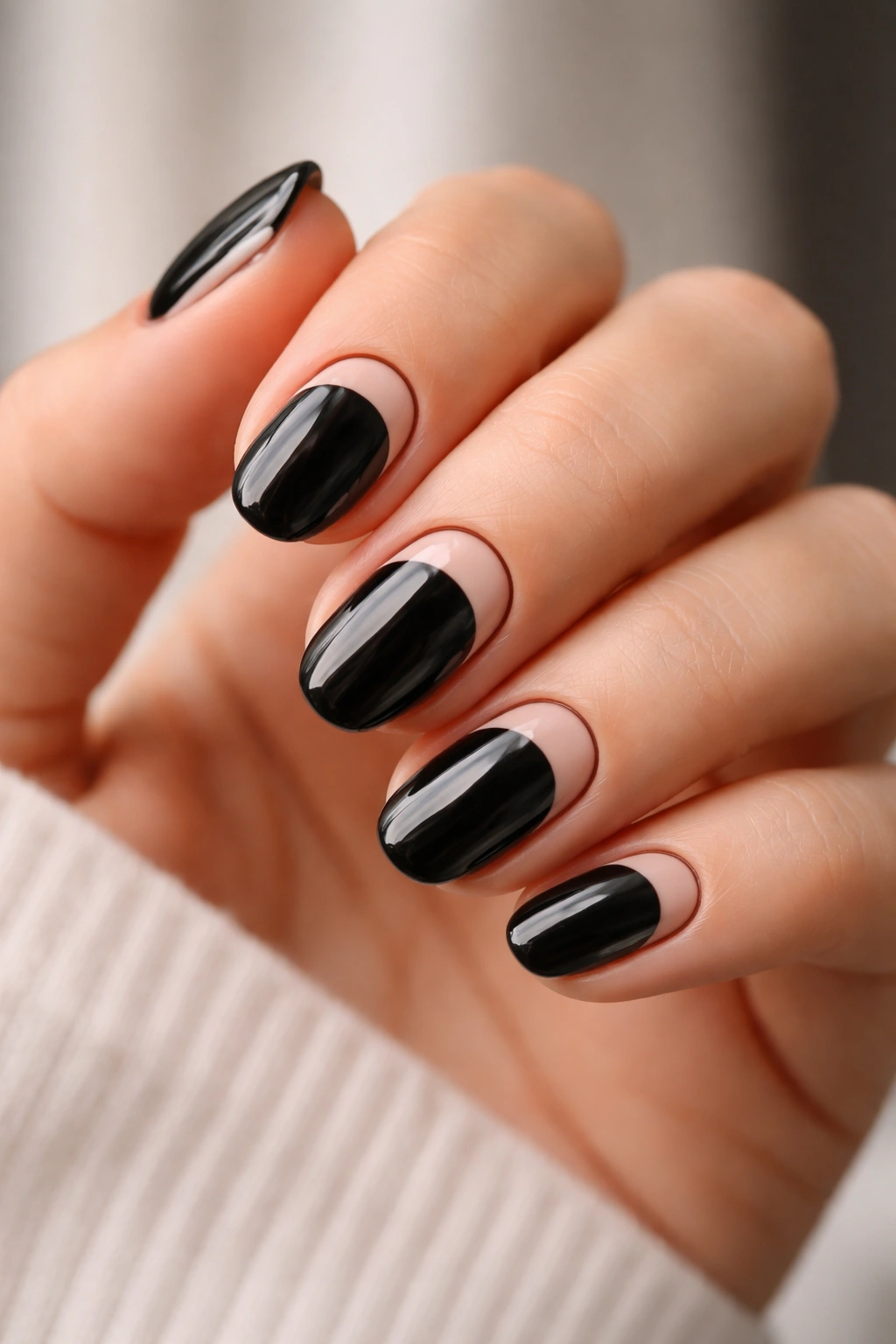 Close-up of short oval black nails with nude cutout tips framed by a thin black outline