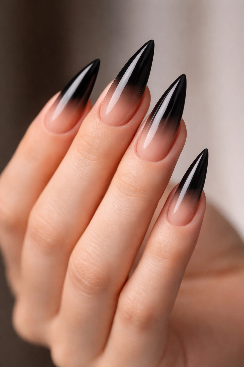 Close-up of black stiletto nails with nude ombre fade
