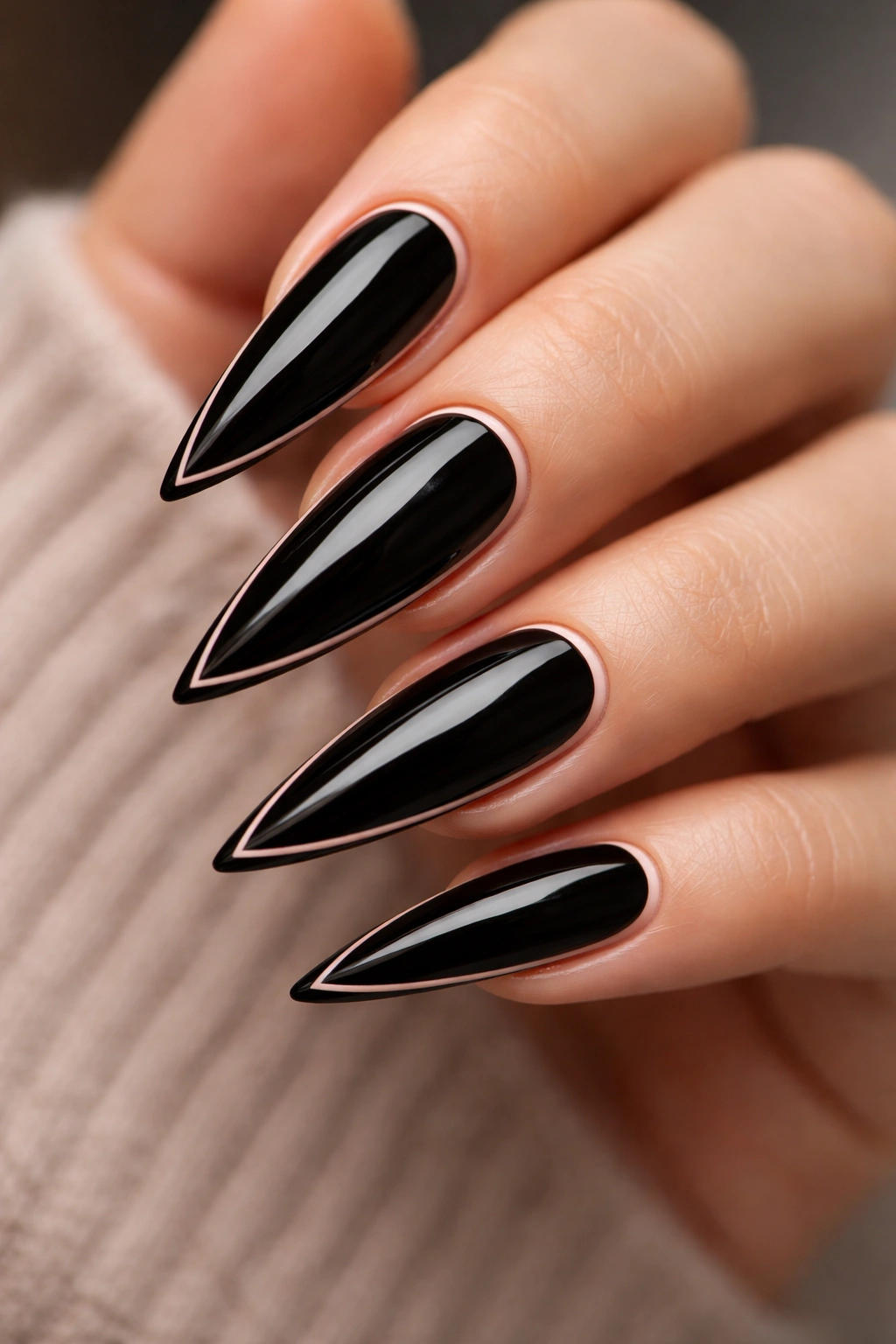 Close-up of black stiletto nails outlined in nude around the edges