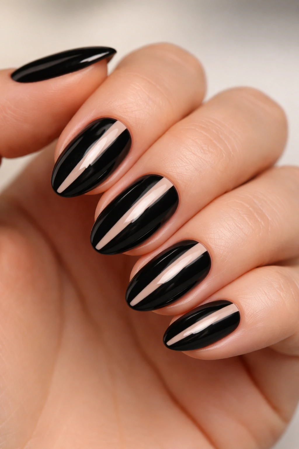 Close-up of short almond nails with a slim nude center stripe and black side framing, glossy finish