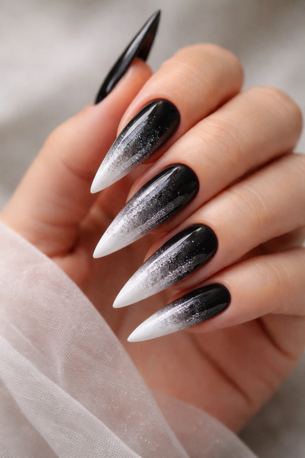 Close-up of black stiletto nails fading to silver and white