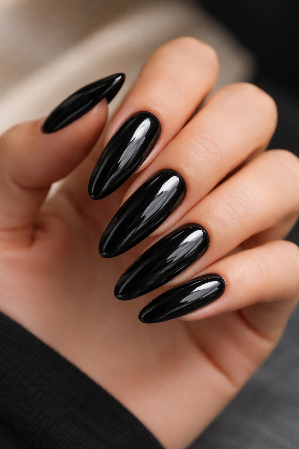 Close-up of ultra-long black oval nails with high-gloss finish on a hand, studio lighting
