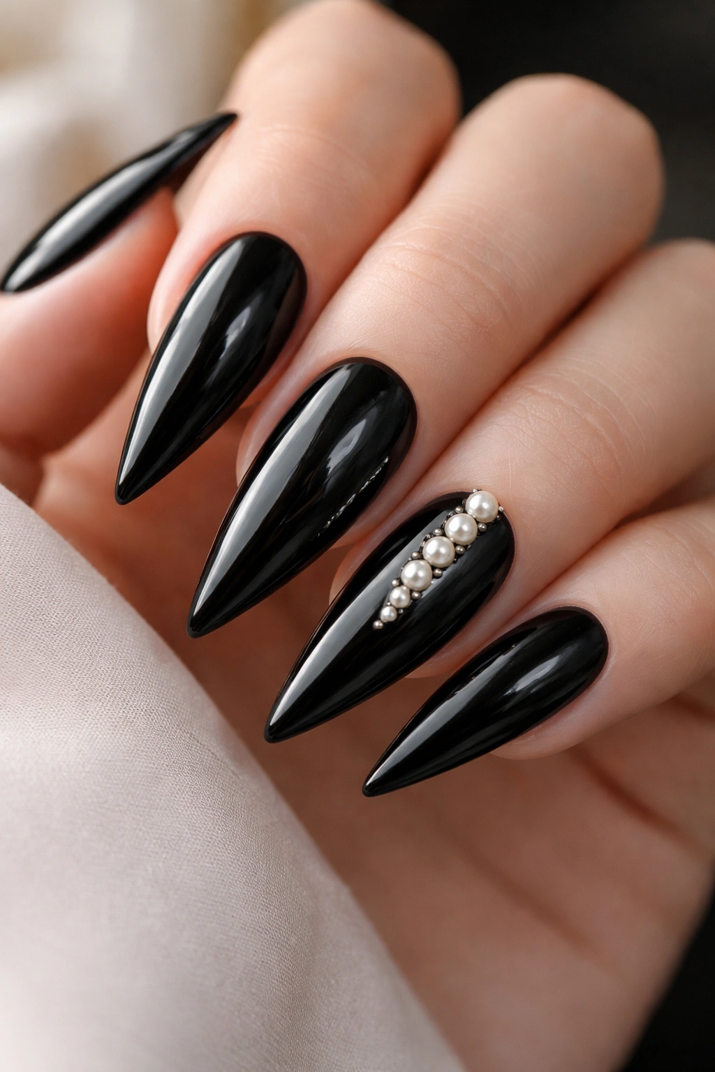 Close-up of black stiletto nails with small pearl accents