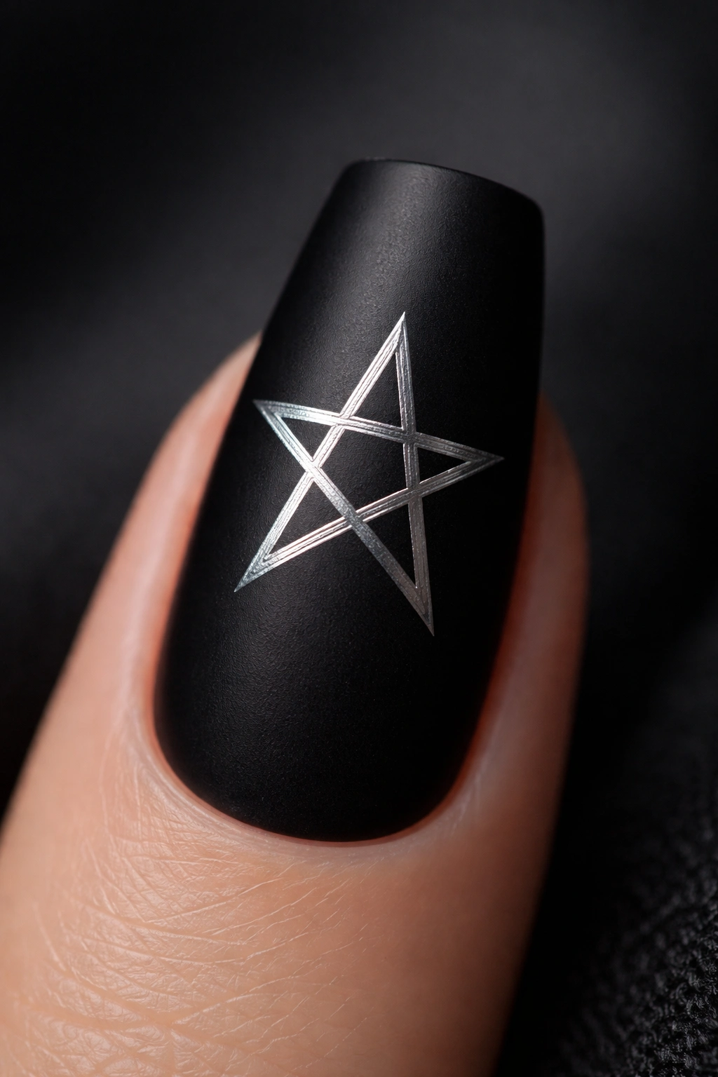 Close-up of a coffin nail with matte black base and silver pentagram accent