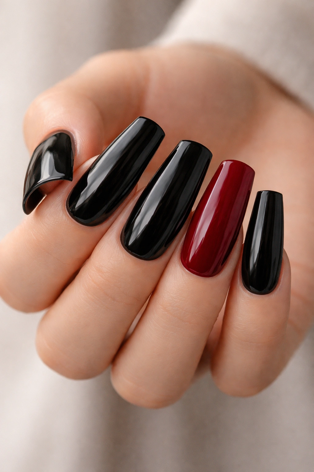 Close-up of black duck nails with a red accent nail
