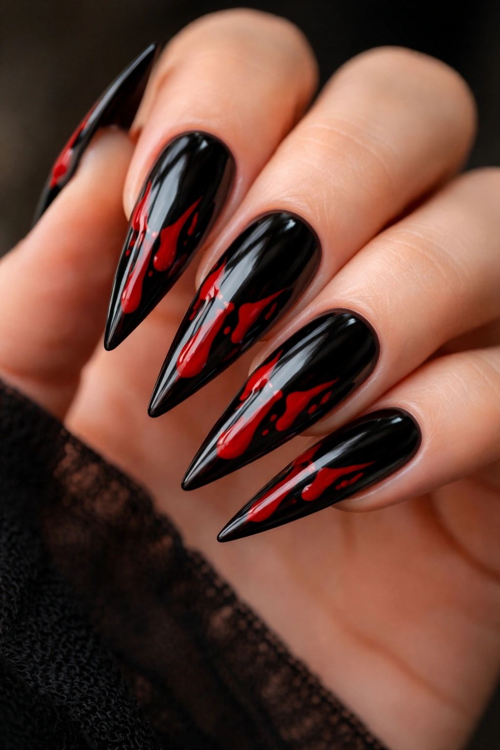 Close-up of black stiletto nails with red blood drip design