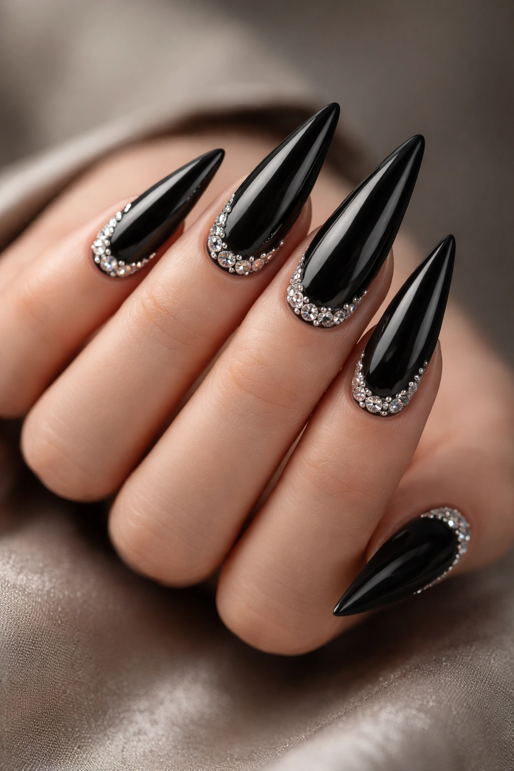 Close-up of black stiletto nails with silver rhinestones on a hand