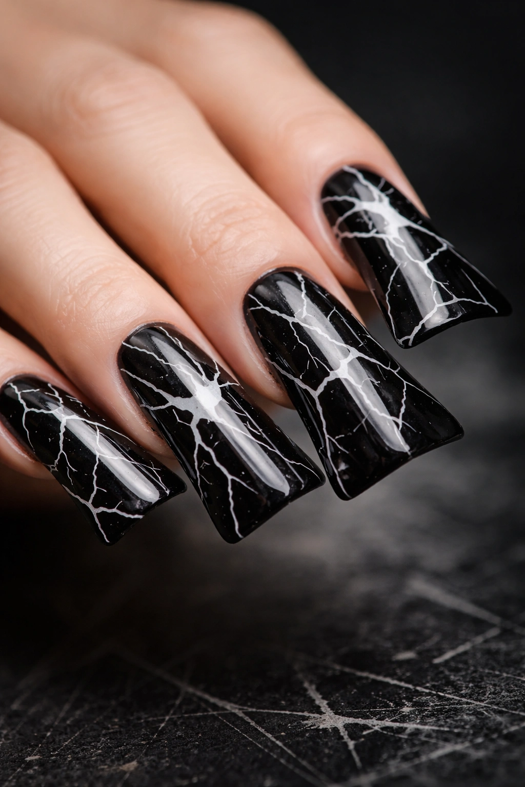 Close up of black nail with white shattered glass pattern on elongated duck nail