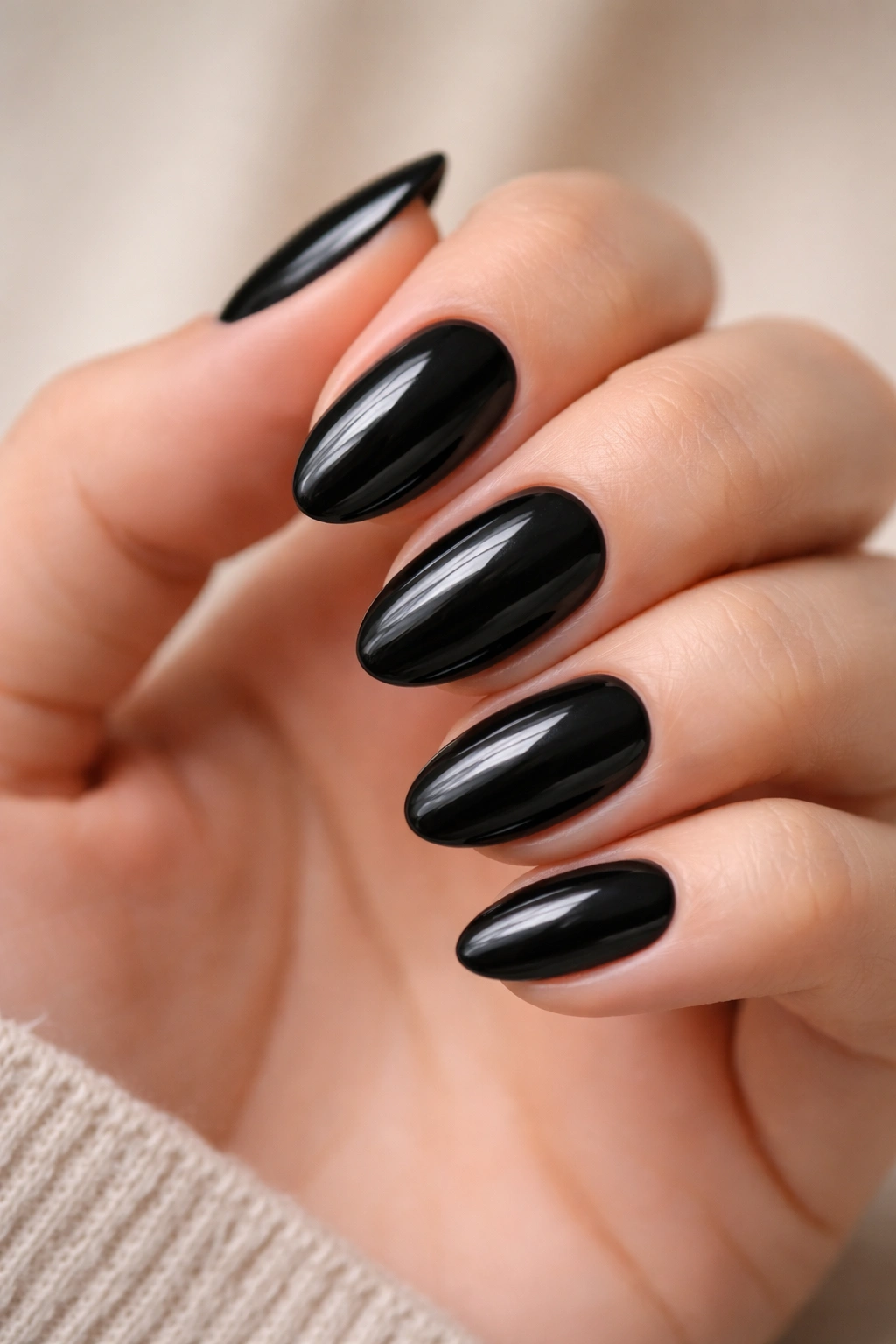 Close-up of glossy black short almond nails.