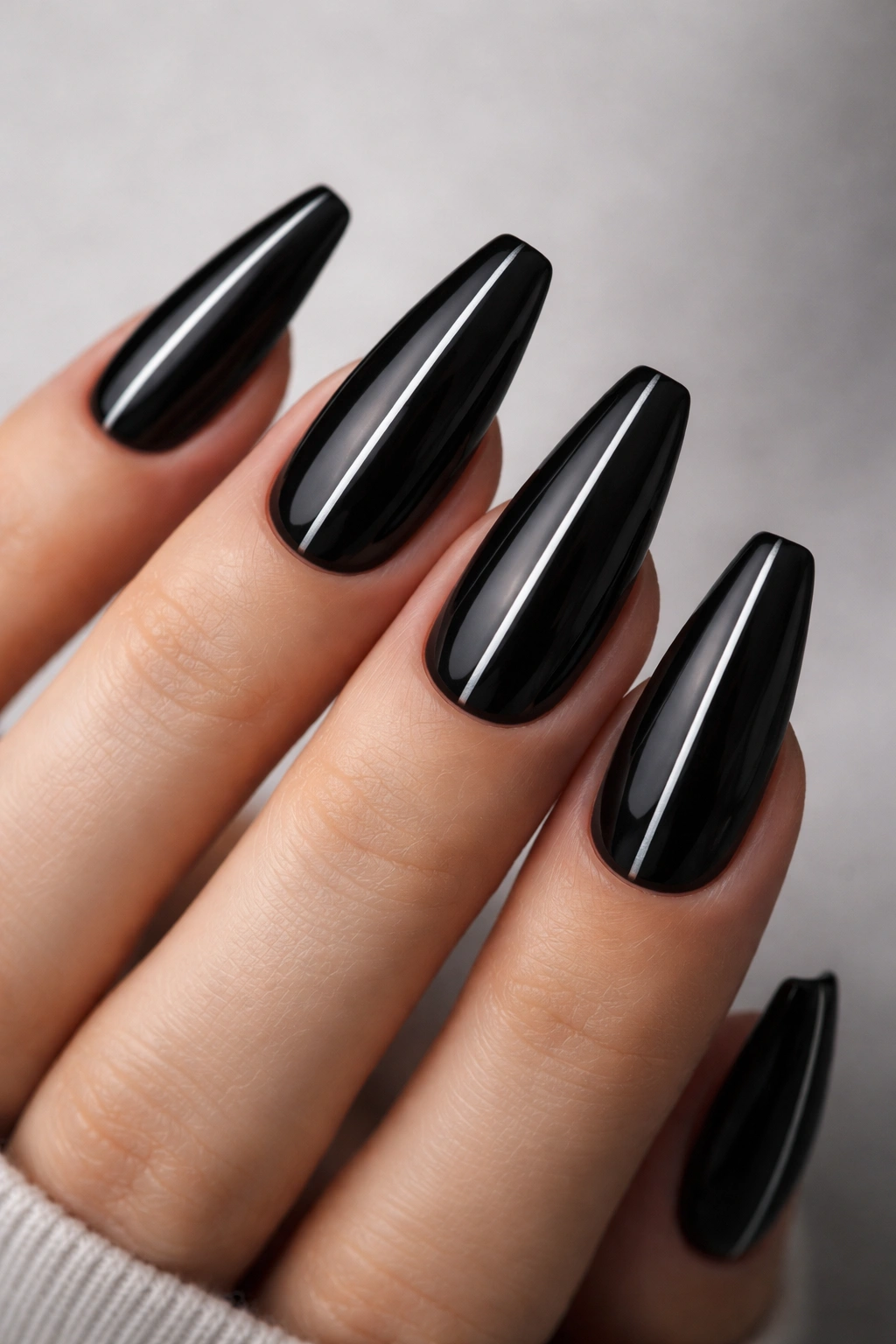 Close-up of black ballerina nails with a thin silver center line on each nail