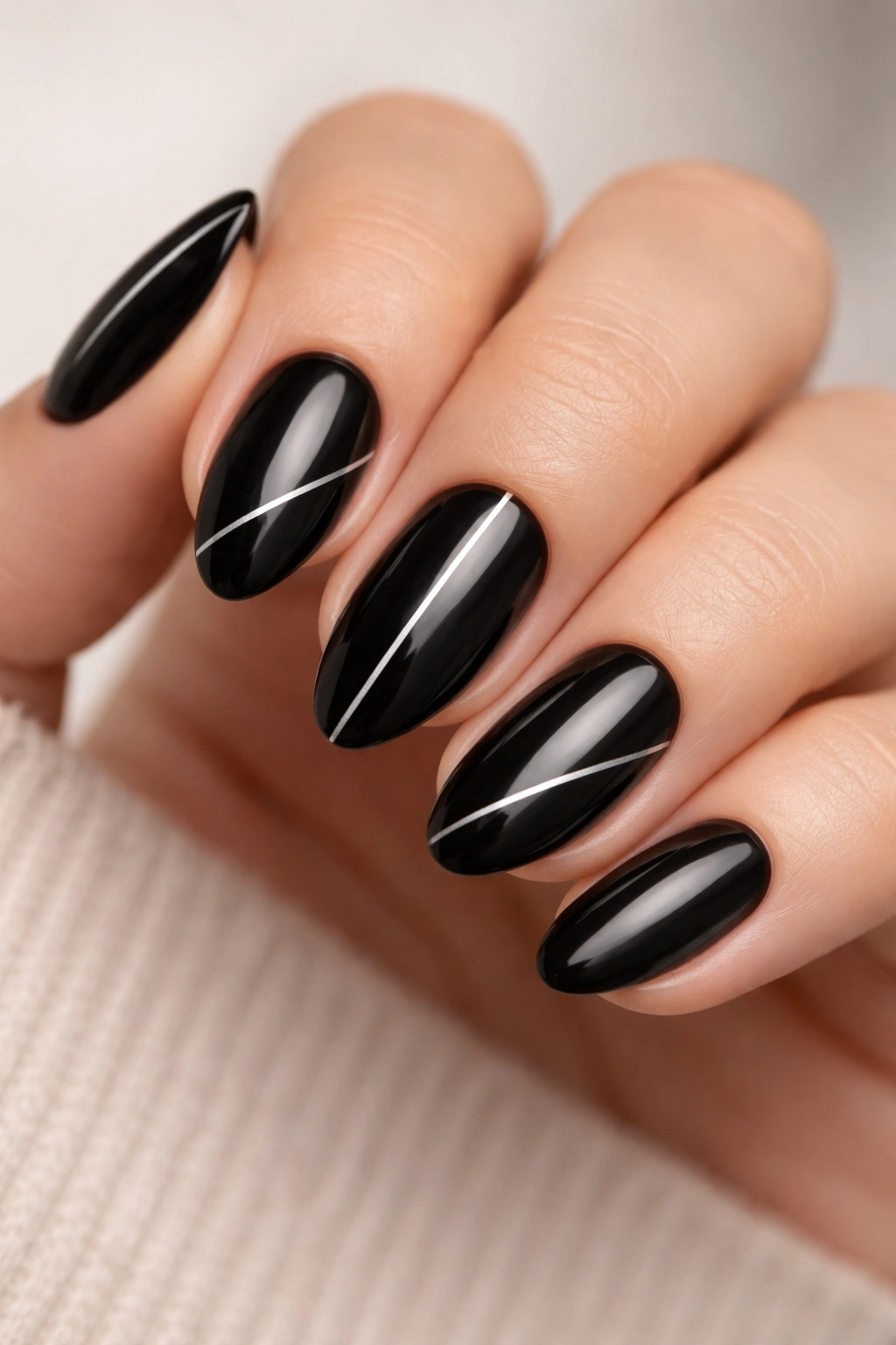 Close-up of black almond nails with thin silver lines