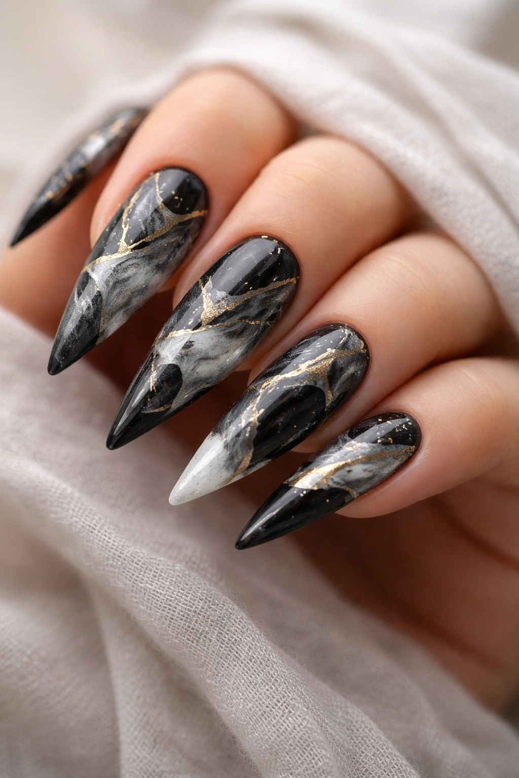 Close-up of black and silver marble nails with gold accents