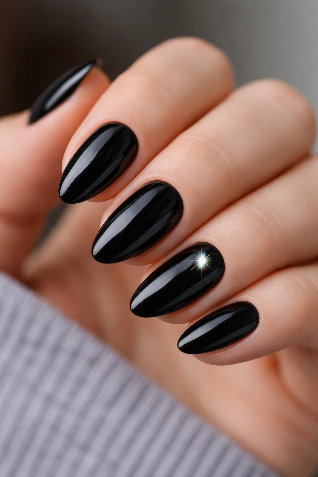 Close-up of black almond nails with one starburst crystal accent