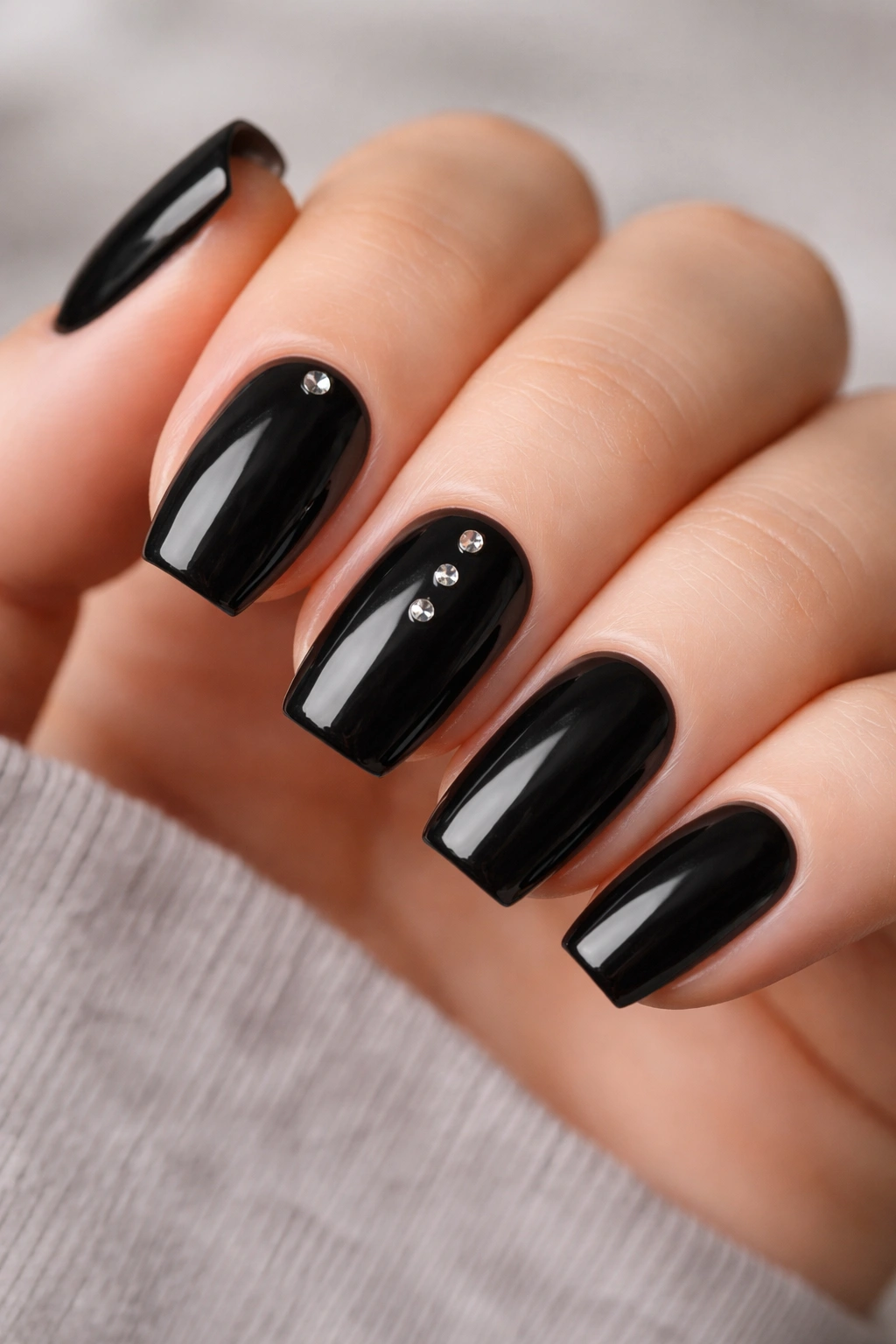 Short black nails with small silver studs placed at cuticle and center