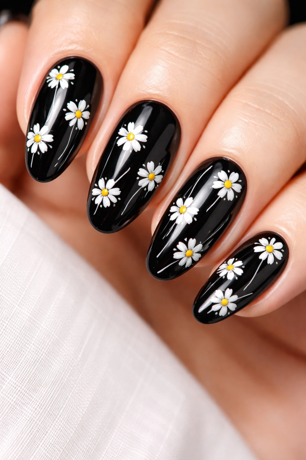 Close-up of black nails with white daisy outlines and yellow centers