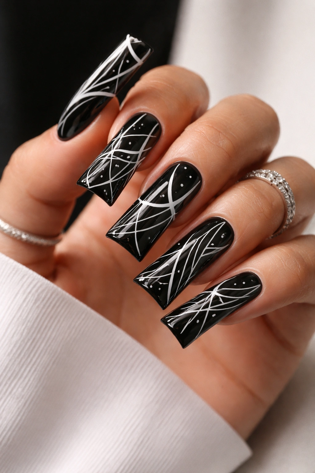 Close-up of black nails with white geometric line art