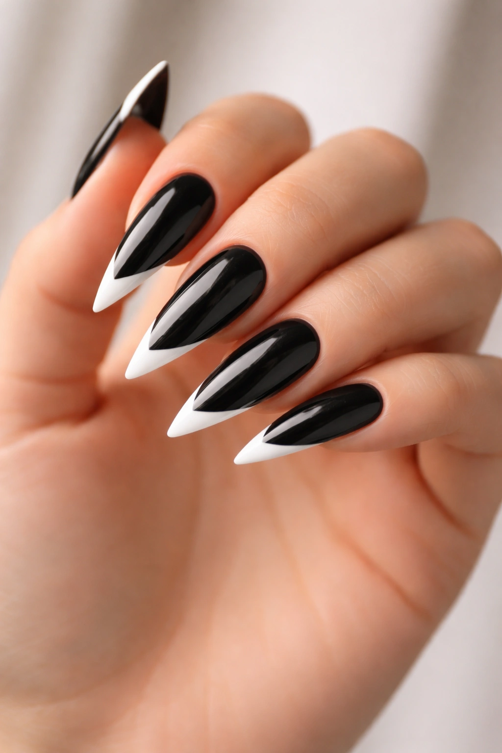 Close-up of glossy black stiletto nails with crisp white tips