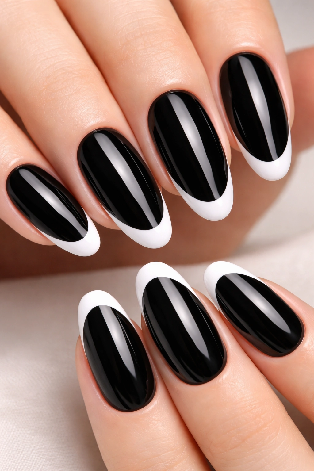 Close-up of oval black nails with pure white French tips on a neutral background