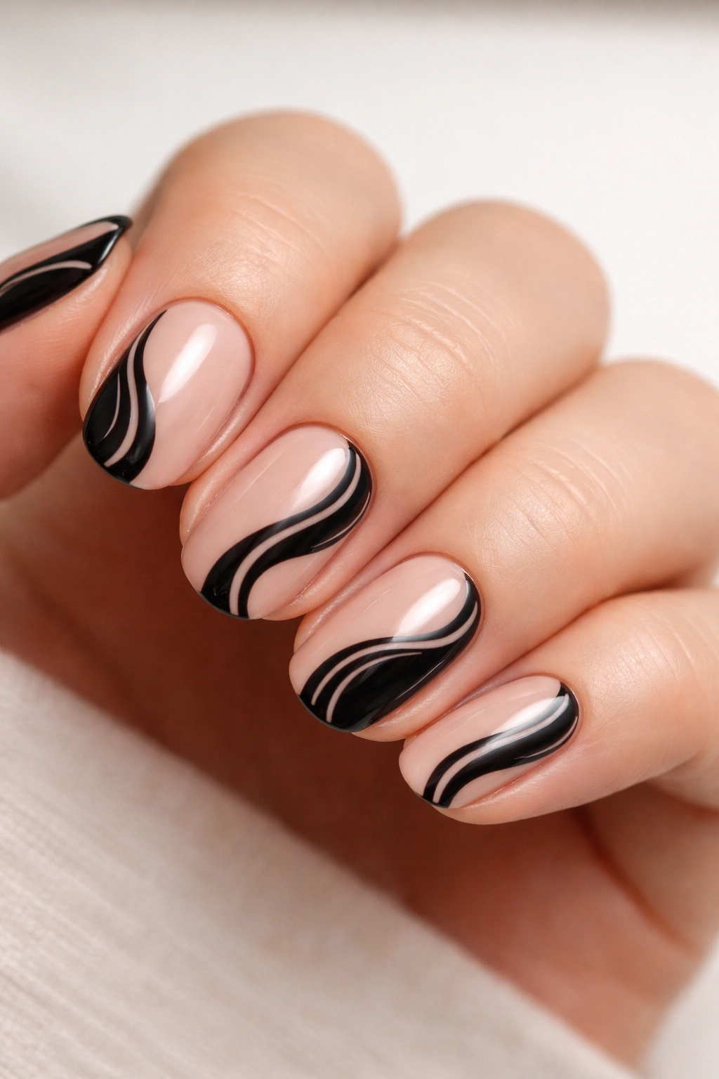 Short oval nails with black abstract waves on nude background