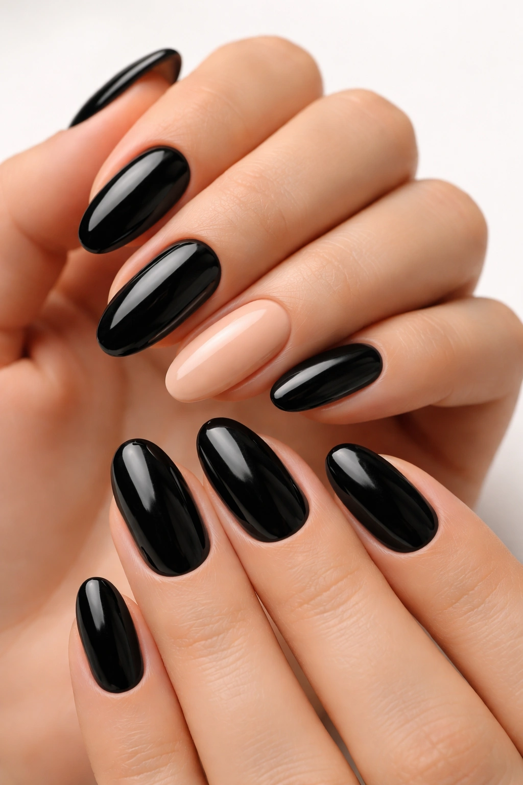 Close-up of black nails with a nude accent nail on the ring finger