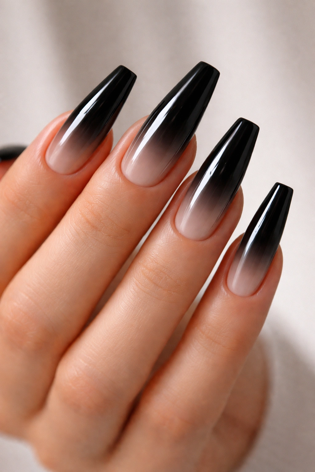 Close-up of black ombre coffin nails fading to clear at tips