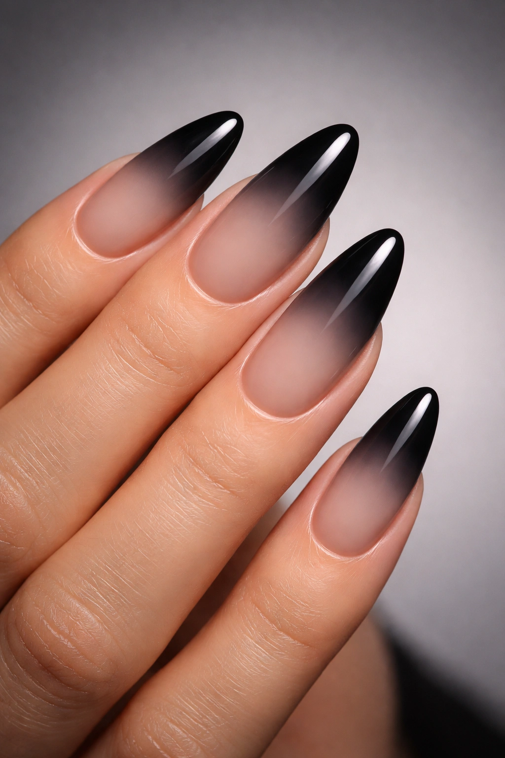 Almond nails with nude to black ombré gradient in a moody finish