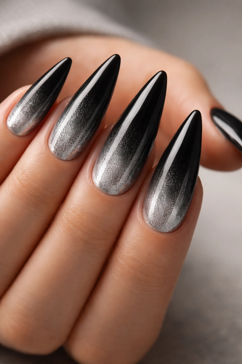 Close-up of long stiletto nails with black to silver ombre gradient